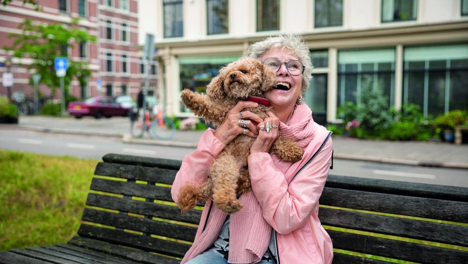 Dame løfter hund op på parkbænk